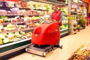 Walk-behind floor scrubber dryer cleaning supermarket aisle floor efficiently