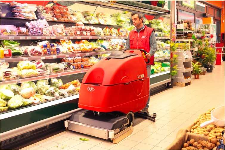 Commercial floor scrubber using disc brushes to clean a supermarket aisle.